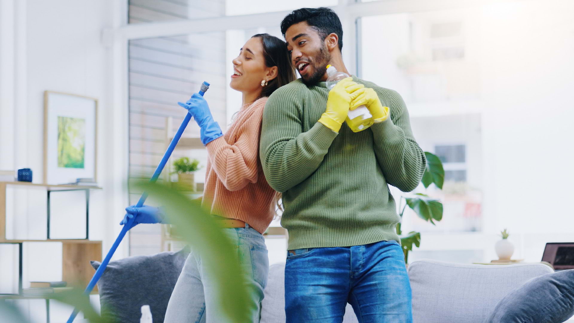A man and a woman tackling cleaning tasks while having fun dancing.